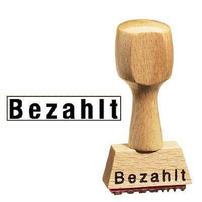 Ein hölzerner bezahlter Stempel mit dem deutschen Wort „Bezahlt
