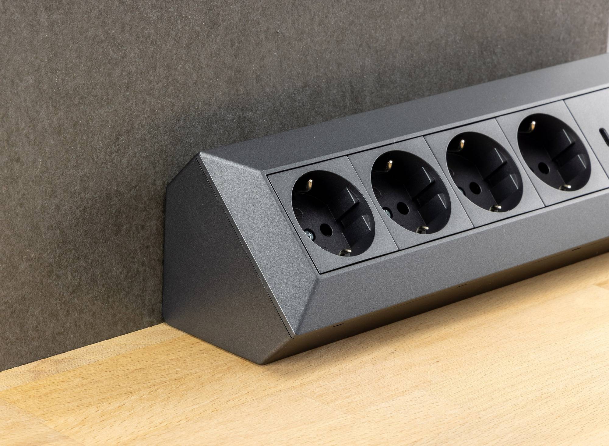 Eine wandmontierte horizontale Einheit mit vier Steckdosen gegen eine graue Oberfläche, entwickelt für Komfort und Zugänglichkeit.