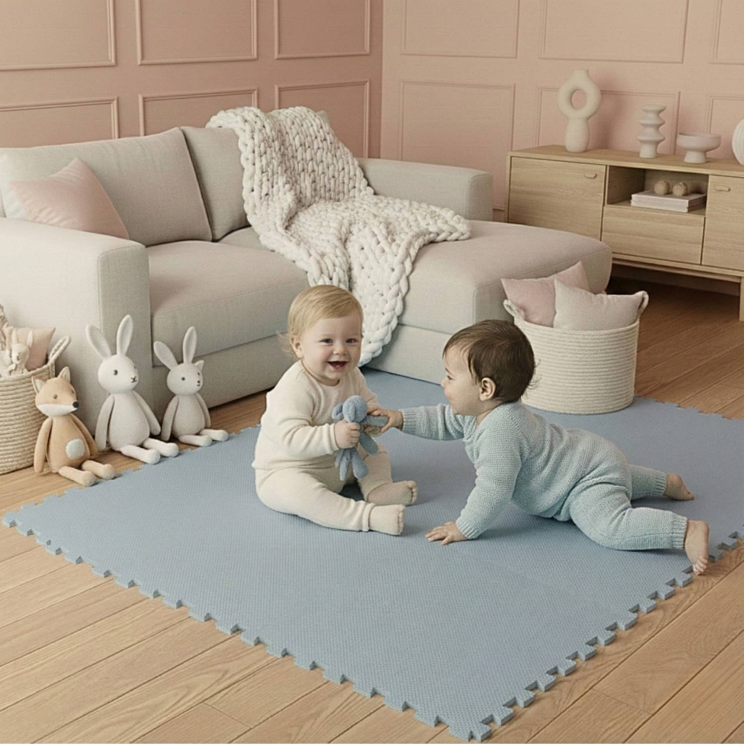 Zwei Kleinkinder spielen auf einer hellblauen Spielmatte in einem gemütlichen Wohnzimmer mit Plüschtieren, einem Sofa und einem dekorierten Regal im Hintergrund.