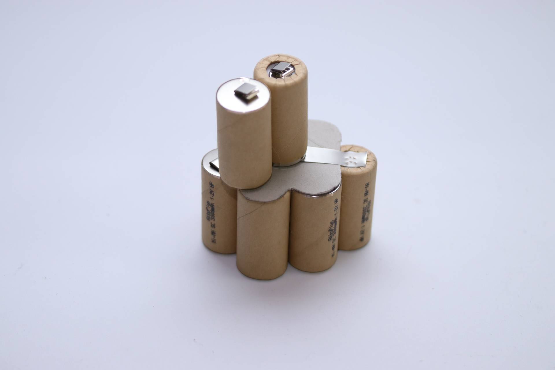 Ein Bündel zylindrischer Batterien, in braunes Papier eingewickelt, eng zusammengruppiert vor einem einfachen weißen Hintergrund.
