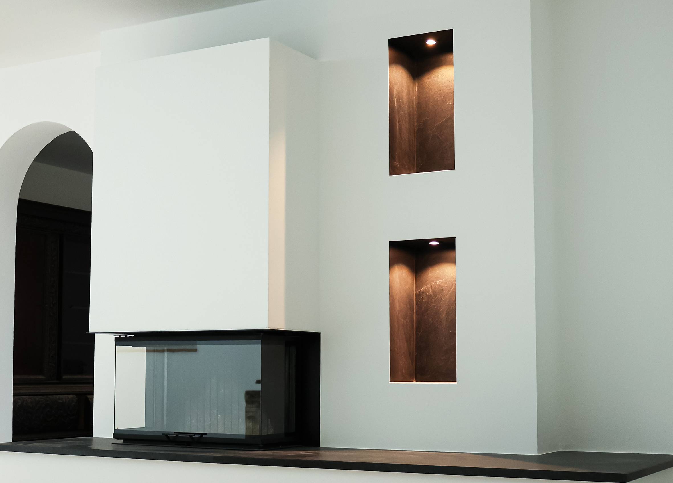 Eine moderne Kücheneinrichtung mit einem eleganten Schwarz-Weiß-Design. Zwei beleuchtete eingelassene Regale sorgen für gedämpftes Ambiente an der Wand.