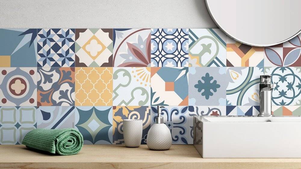 Badezimmerspüle mit farbenfroher geometrisch gemusterter Fliesenwand, Seifenspendern und einem grünen Handtuch auf der Arbeitsplatte