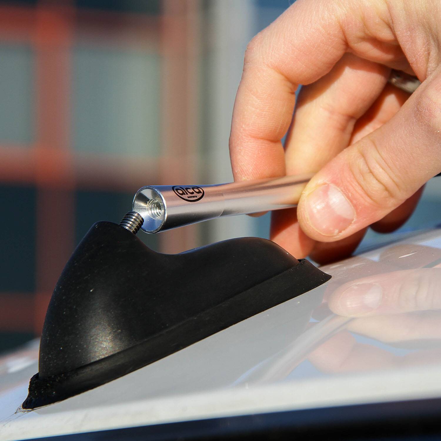 Eine Hand stellt eine metallische Autoantennen an einer schwarzen Basis ein.