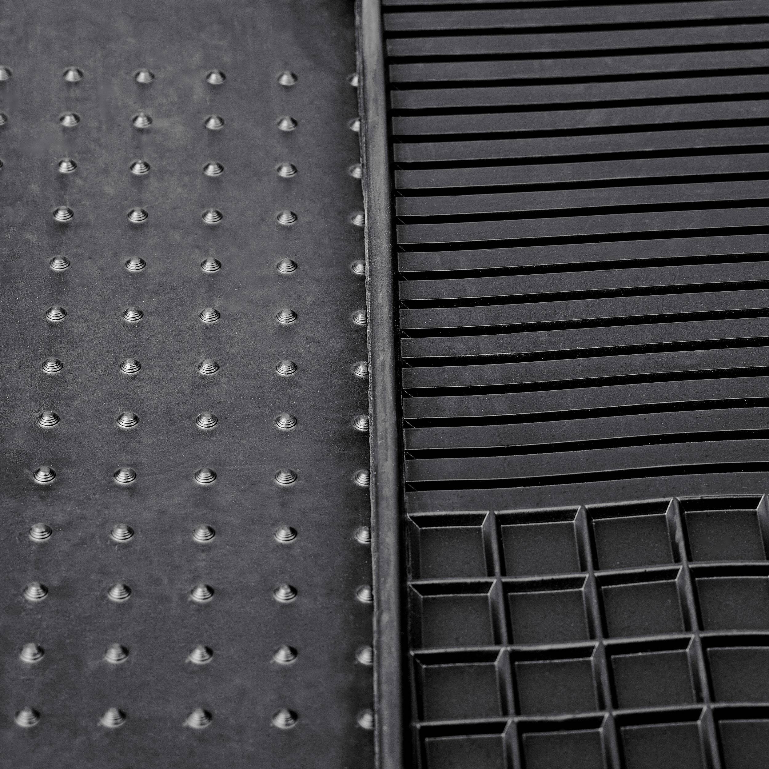 Strukturierte schwarze Gummimatte mit drei Abschnitten: erhabene Punkte, horizontale Rippen und Rastermuster. Entwickelt zur Bereitstellung von Griffigkeit und Drainage.