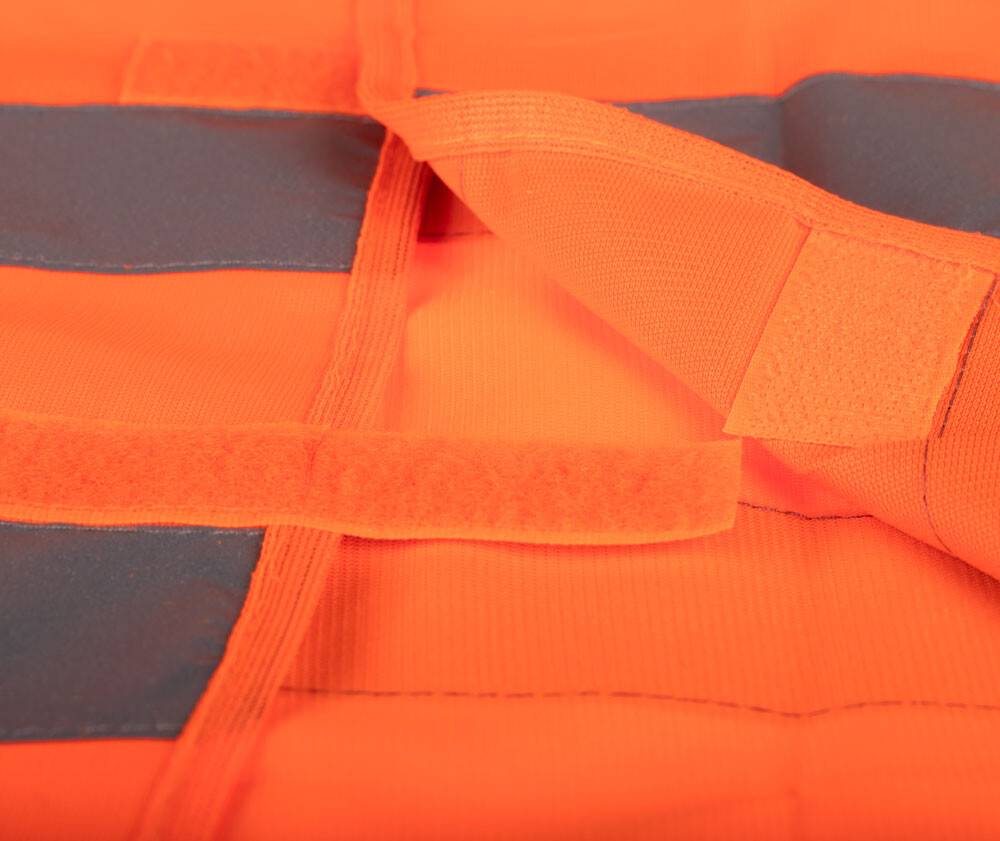 Nahaufnahme eines orangefarbenen Stoffes mit grauen Streifen, mit einem teilweise geöffneten Klettverschlussstreifen, wahrscheinlich Teil eines Sicherheitskleides oder einer Weste.