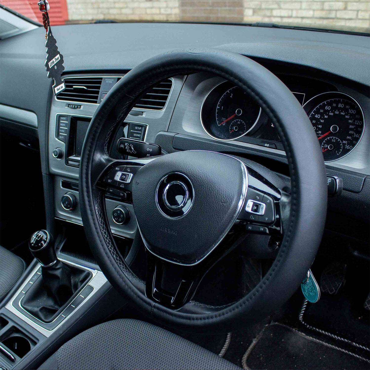 Automobilinnenseite mit Lenkrad, Armaturenbrett, manuellem Schaltknüppel und Infotainment-System, das ein modernes, sauberes Design zeigt.