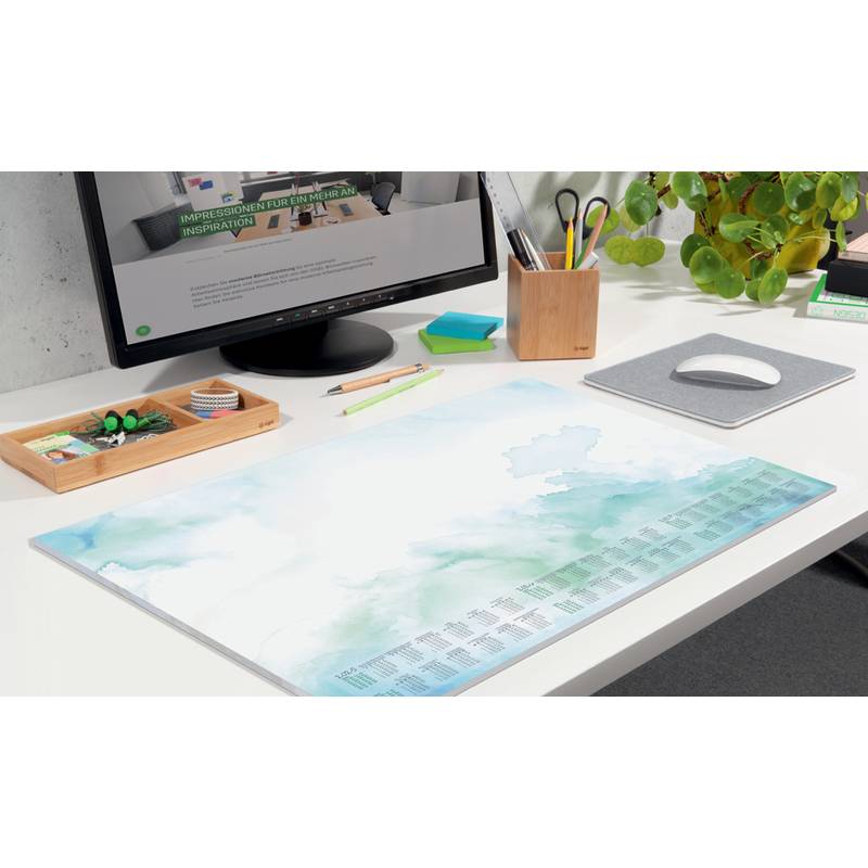 Ein aufgeräumter, ordentlicher Schreibtisch mit einem Computermonitor, auf dem Text zu sehen ist, einem großen Kalender, Stiften und einer Pflanze. Die Szene vermittelt Produktivität.