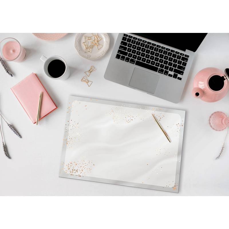 Ein Laptop, eine rosa Teekanne, Kaffee, ein Notizbuch, Bleistifte und Schreibwaren sind ordentlich auf einem weißen Schreibtisch angeordnet und schaffen einen organisierten Arbeitsplatz.