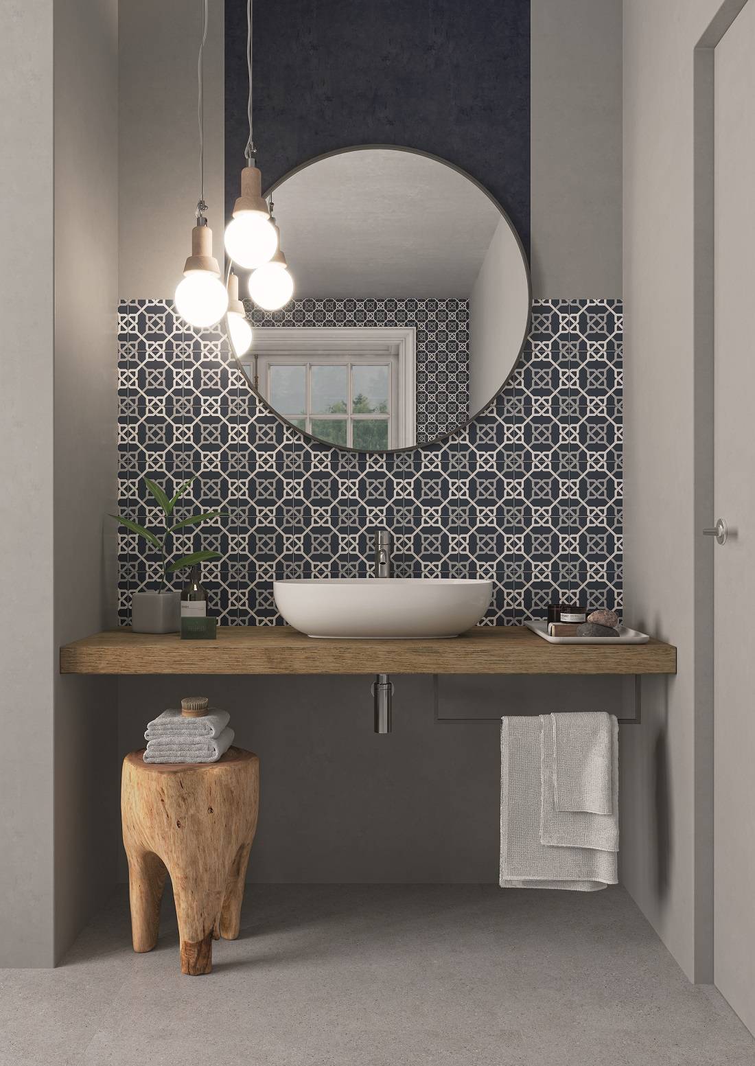 Modernes Badezimmer-Waschtisch mit rundem Spiegel, Pendelleuchten, weißem Aufsatzwaschbecken, gemustertem Fliesenspiegel, Holzarbeitsplatte und Handtuchtruhe.
