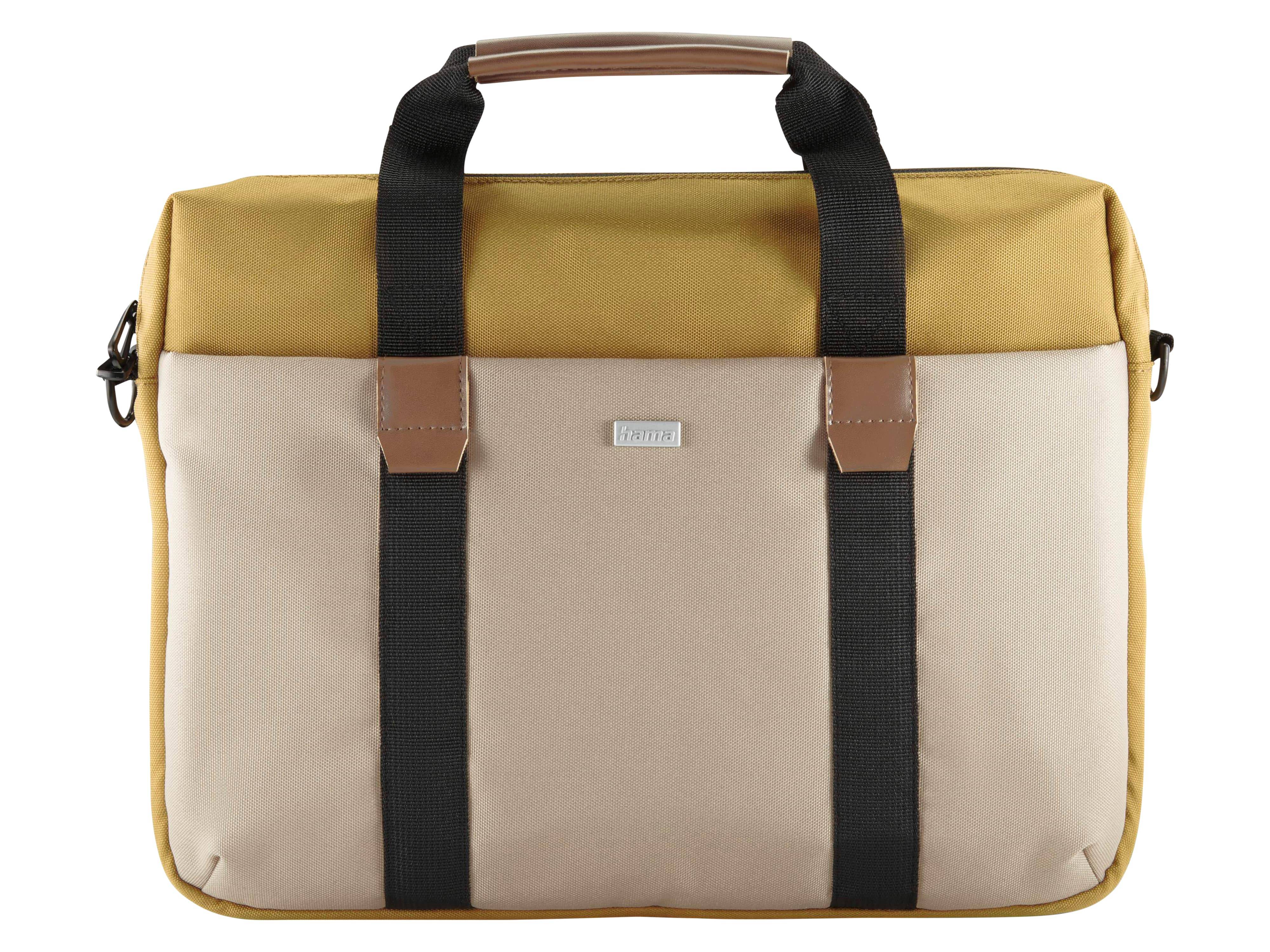 Eine beige und senfgelbe Tasche mit schwarzen Trägern und Lederakzenten, mit einem kleinen Metallnamenschild an der Vorderseite, vor einem weißen Hintergrund.