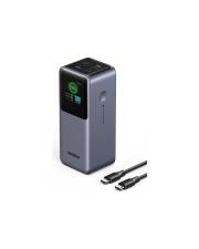Tragbare Powerbank mit kleinem Display und zwei Ladekabeln daneben, auf weißem Hintergrund abgebildet.