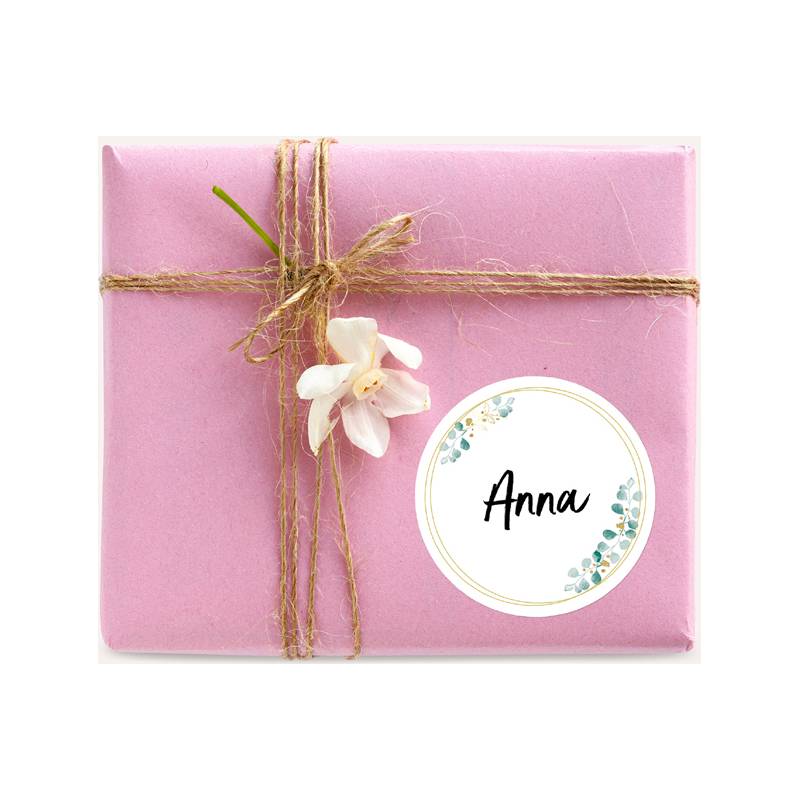 Ein rosa Geschenk, mit Garn umwickelt, versehen mit einer weißen Blume und einem runden Etikett mit der Aufschrift 