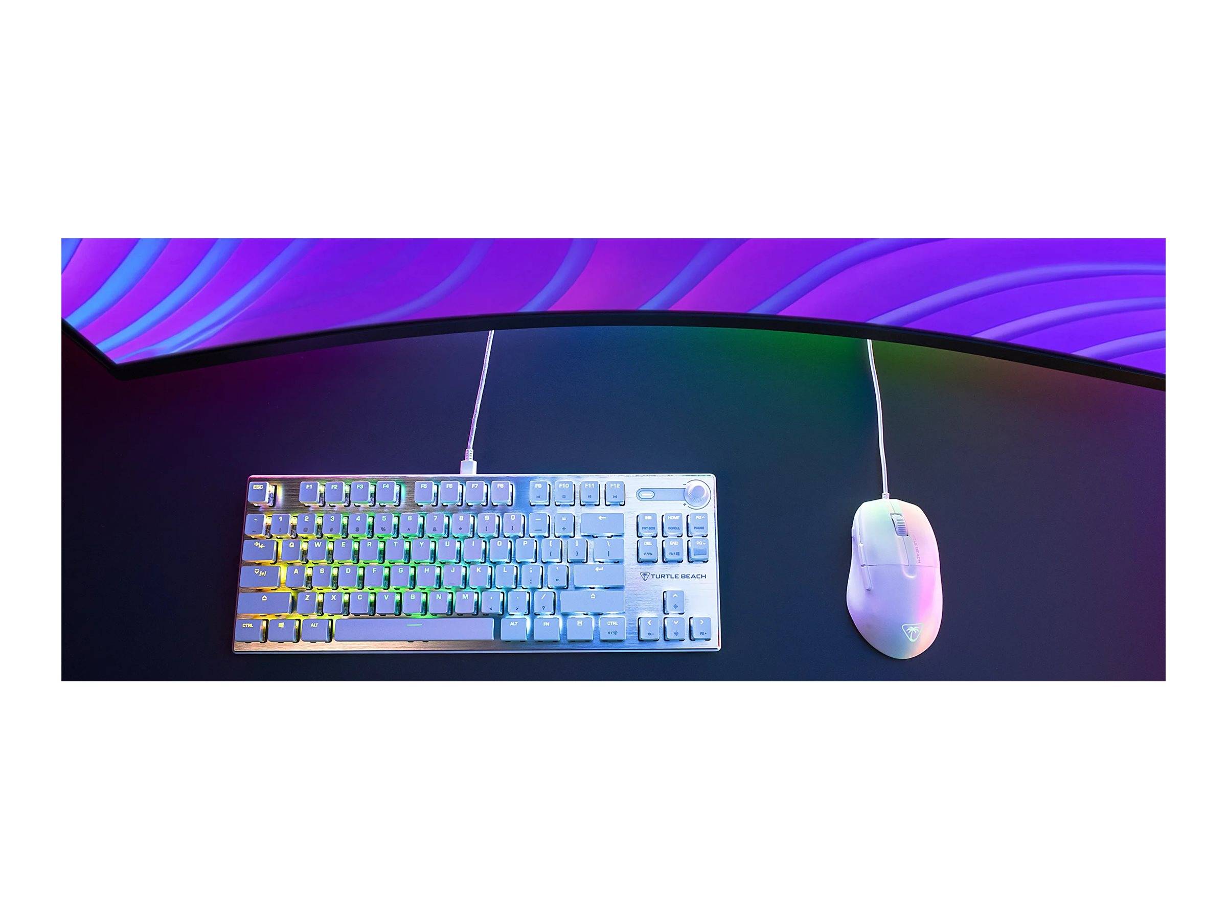 Eine bunte RGB-hintergrundbeleuchtete Tastatur und eine weiße Gaming-Maus liegen auf einem dunklen Schreibtisch unter einem gekrümmten Monitor, der einen lebendigen Farbverlauf anzeigt.