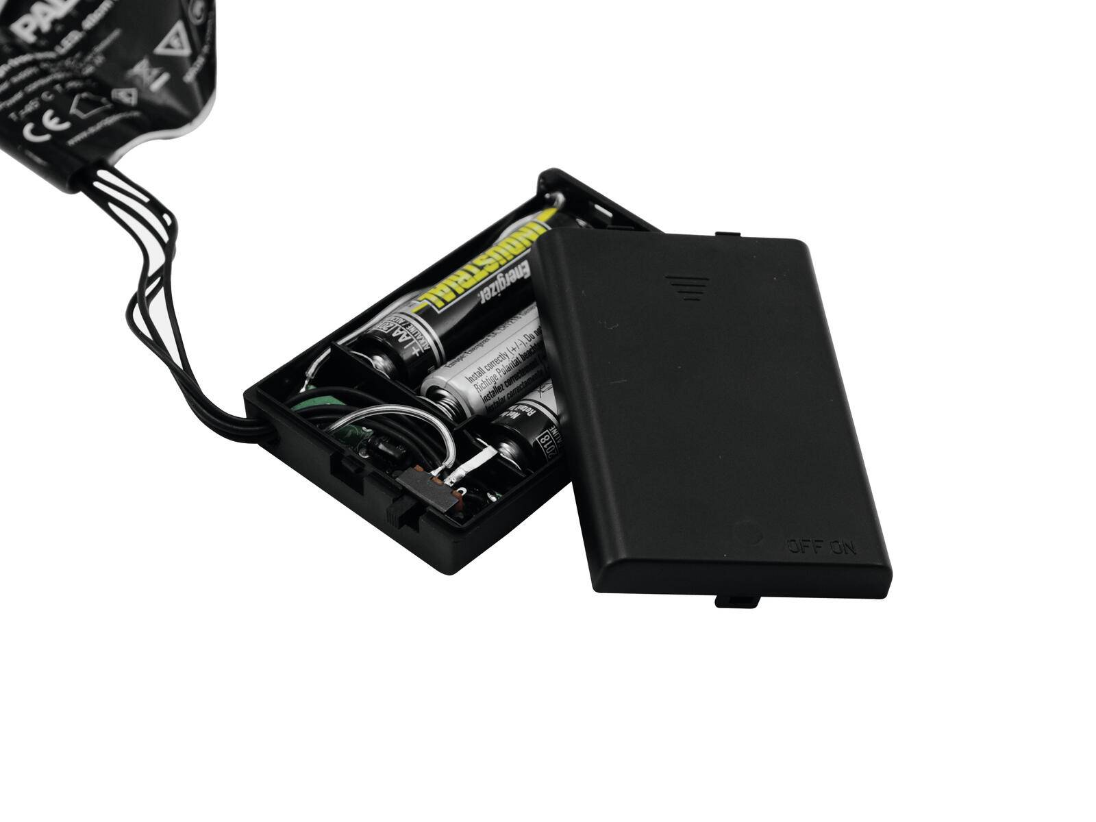 Ein offenes schwarzes Batteriefach mit zwei AA-Batterien, teilweise mit Drähten auf der linken Seite verbunden. Der Deckel liegt in der Nähe.