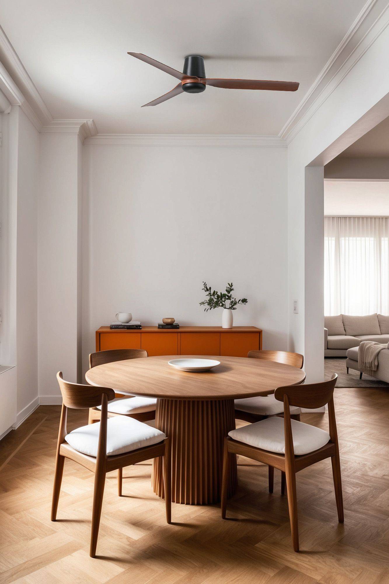 Ein modernes Esszimmer mit einem runden Holztisch, vier Stühlen und einer kleinen Vase auf dem Sideboard. Im Hintergrund ist ein angrenzender Wohnbereich sichtbar.