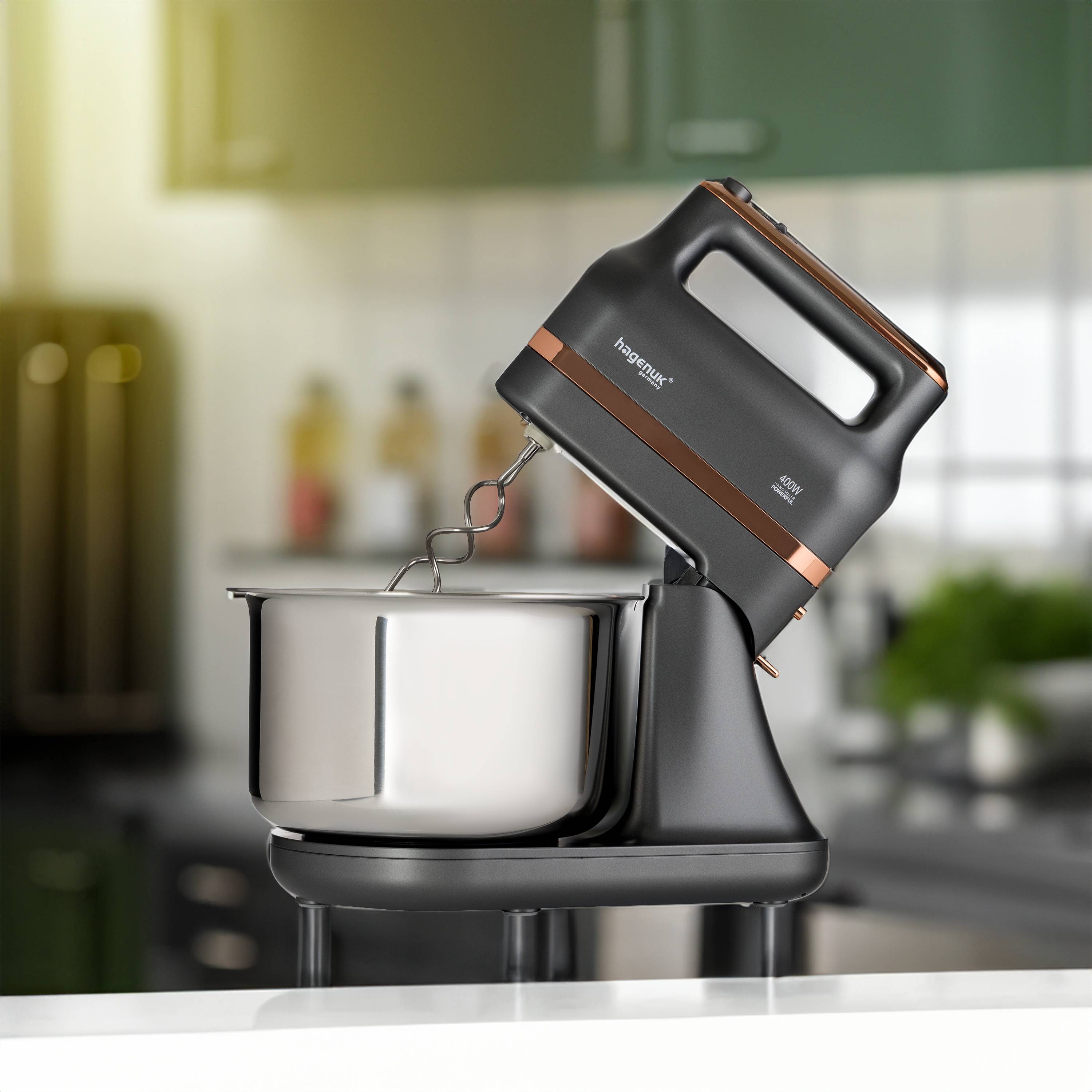 Ein schwarzer Standmixer mit edelstahlerner Schüssel steht auf einer Küchentheke. Der Mixer hat Kupferakzente und ist in einer modernen Küche angebracht.