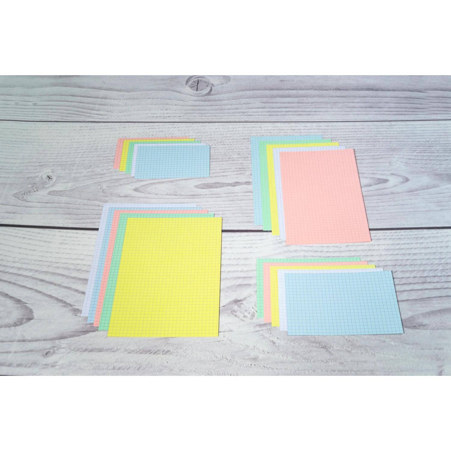 Mehrere Stapel von Pastellfarbigen Millimeterpapier-Karten oder Haftnotizen, die auf einer hellen Holzoberfläche angeordnet sind, darunter gelbe, rosa, blaue und grüne Blätter.