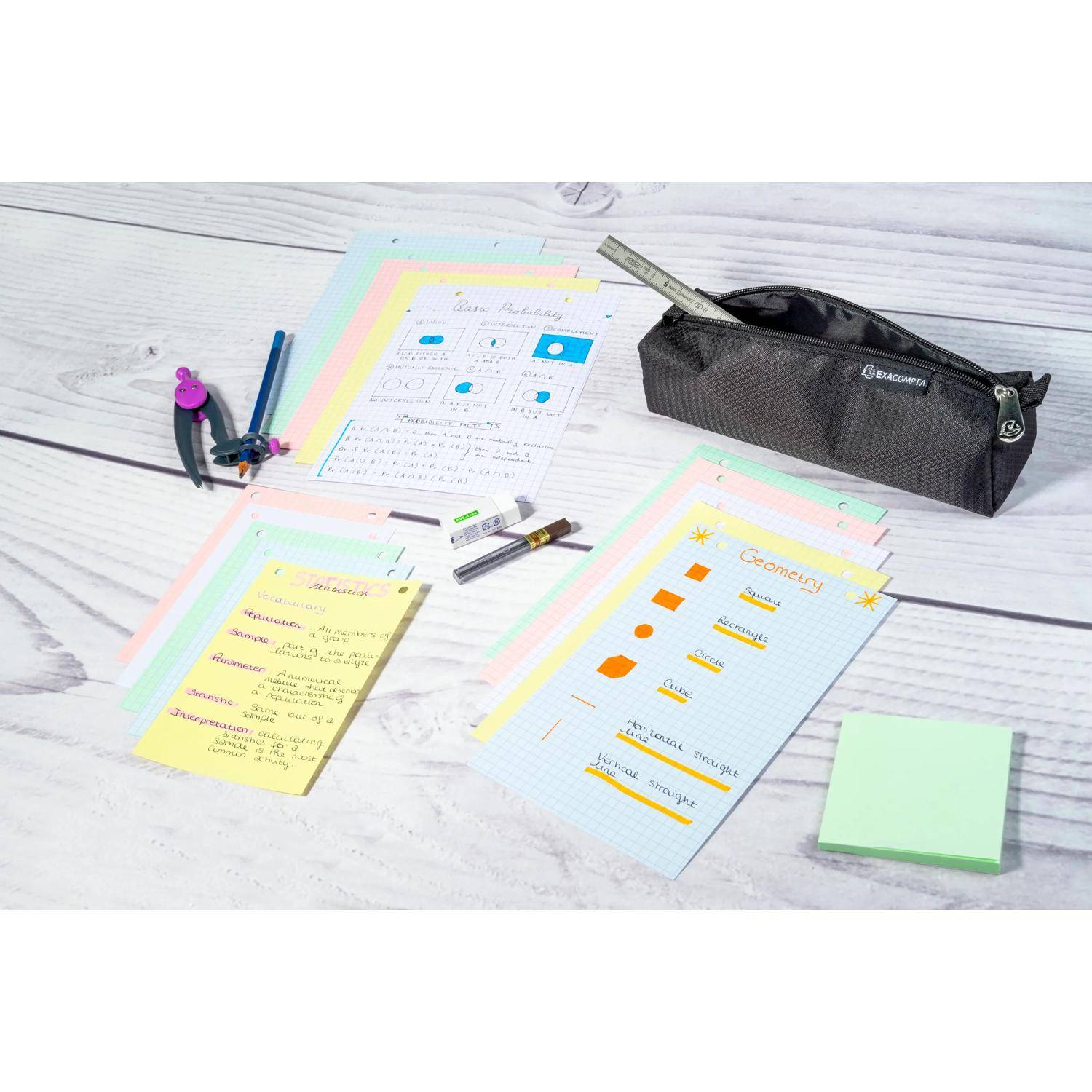 Schreibtisch mit Bullet-Journal-Seiten, Haftnotizen, Stiften, Kompass, Lineal und Federmäppchen auf einer weißen Holzoberfläche angeordnet