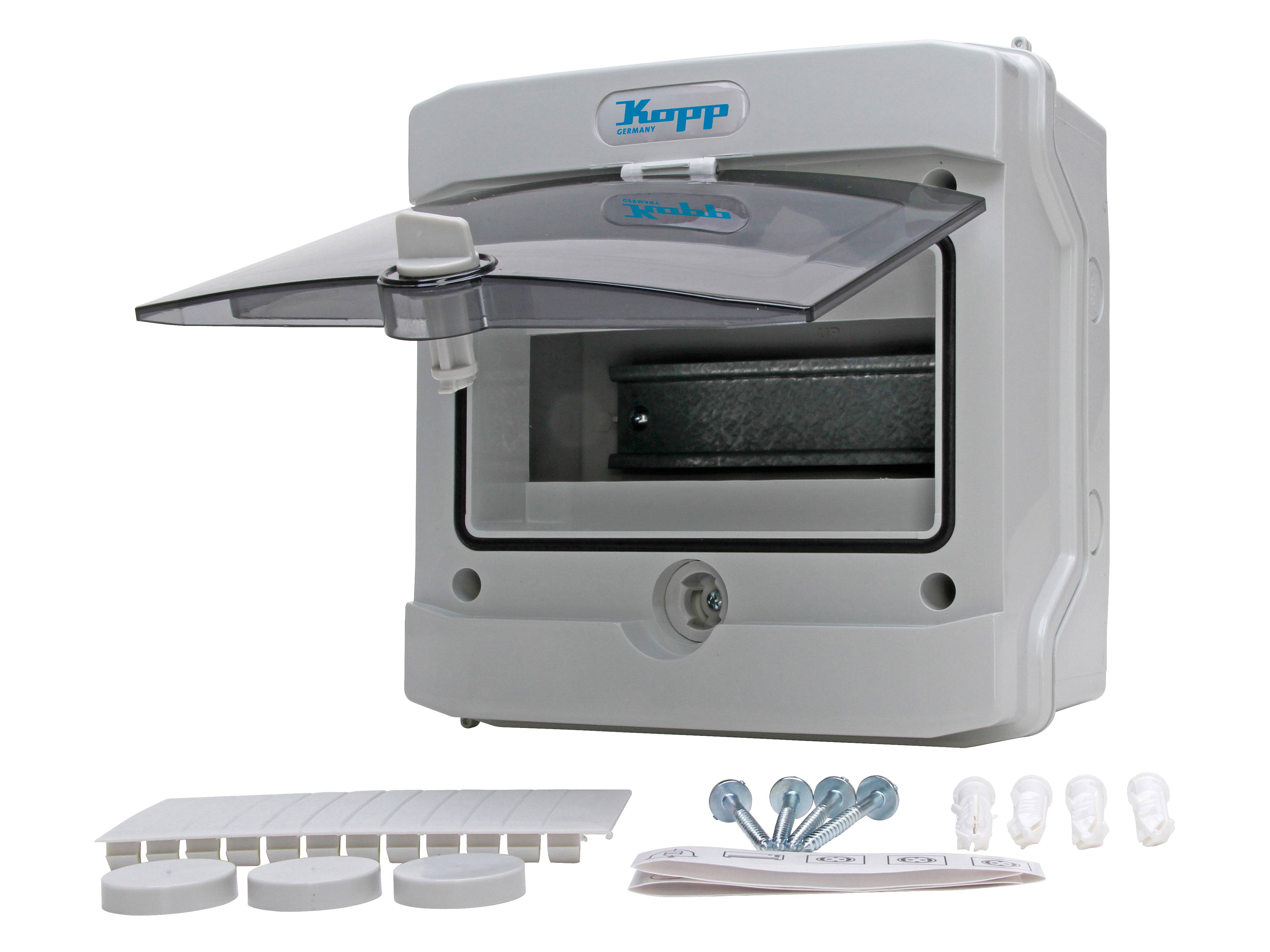 Elektrischer Verteilkasten mit transparentem Deckel offen, der Befestigungslöcher im Inneren zeigt. Enthält Schrauben und Kunststoffkappen für die Installation.