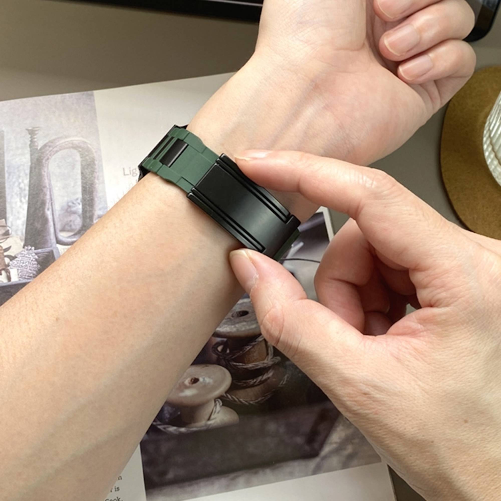 Nahaufnahme eines Handgelenks, das eine schwarze und grüne verstellbare Uhr oder ein Armband trägt, während eine Hand die Schließe befestigt.