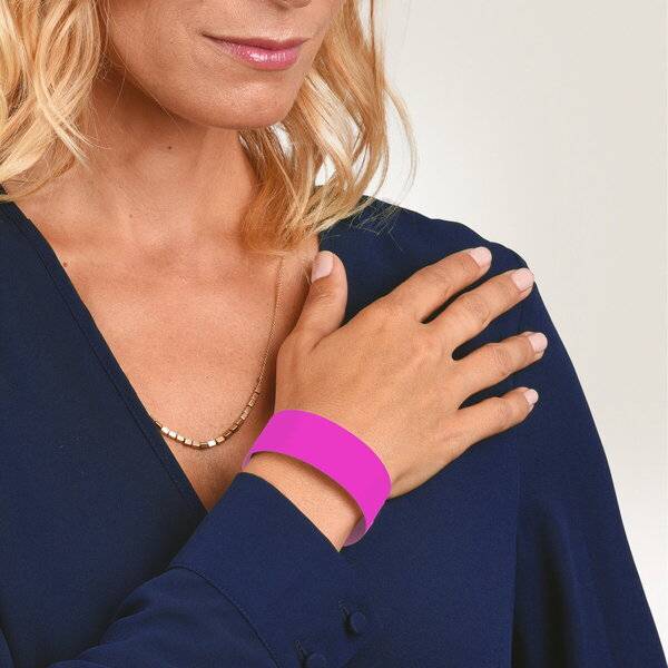 Nahaufnahme einer Frau, die ein rosa Armband trägt, mit ihrer Hand auf ihrer Schulter ruhend und einem dunkelblauen Oberteil sichtbar.