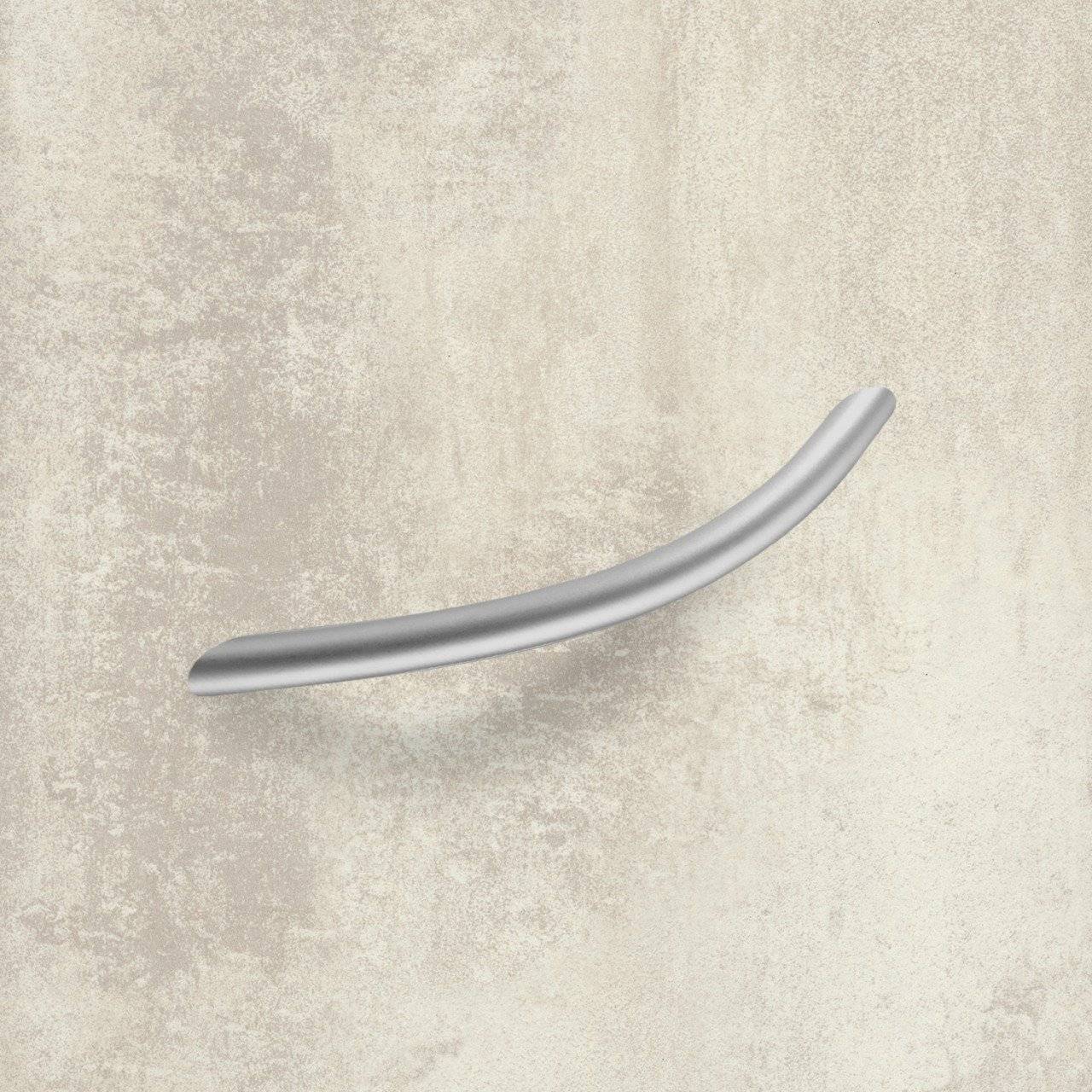 Ein gebogener silberner Griff auf strukturiertem beigem Hintergrund, möglicherweise Teil von Möbeln oder Schrankwerk, ohne sichtbare Etiketten oder zusätzlichen Kontext.