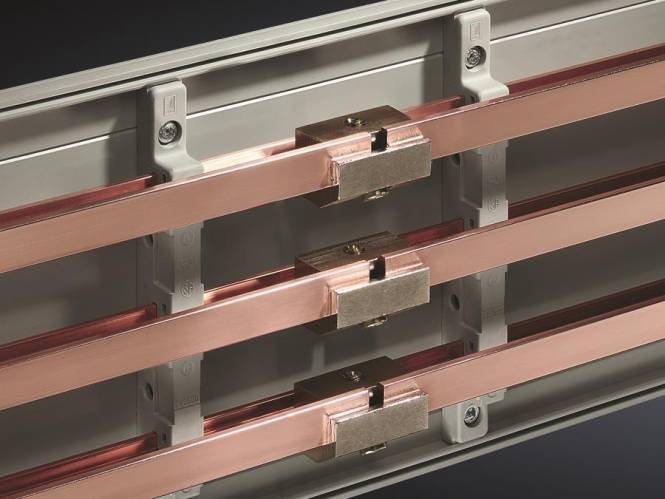 Drei kupferne Sammelschienen, horizontal auf einem Schaltschrank montiert, mit metallischen Verbindern, die sie sichern.
