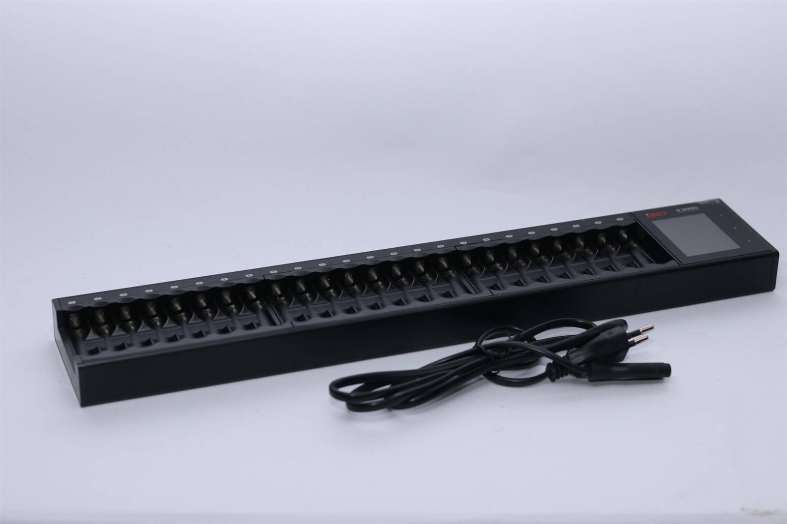 Eine schwarze Steckerleiste mit mehreren Steckdosen liegt auf einer weißen Oberfläche, mit einem angeschlossenen Stromkabel, das aufgewickelt daneben liegt.