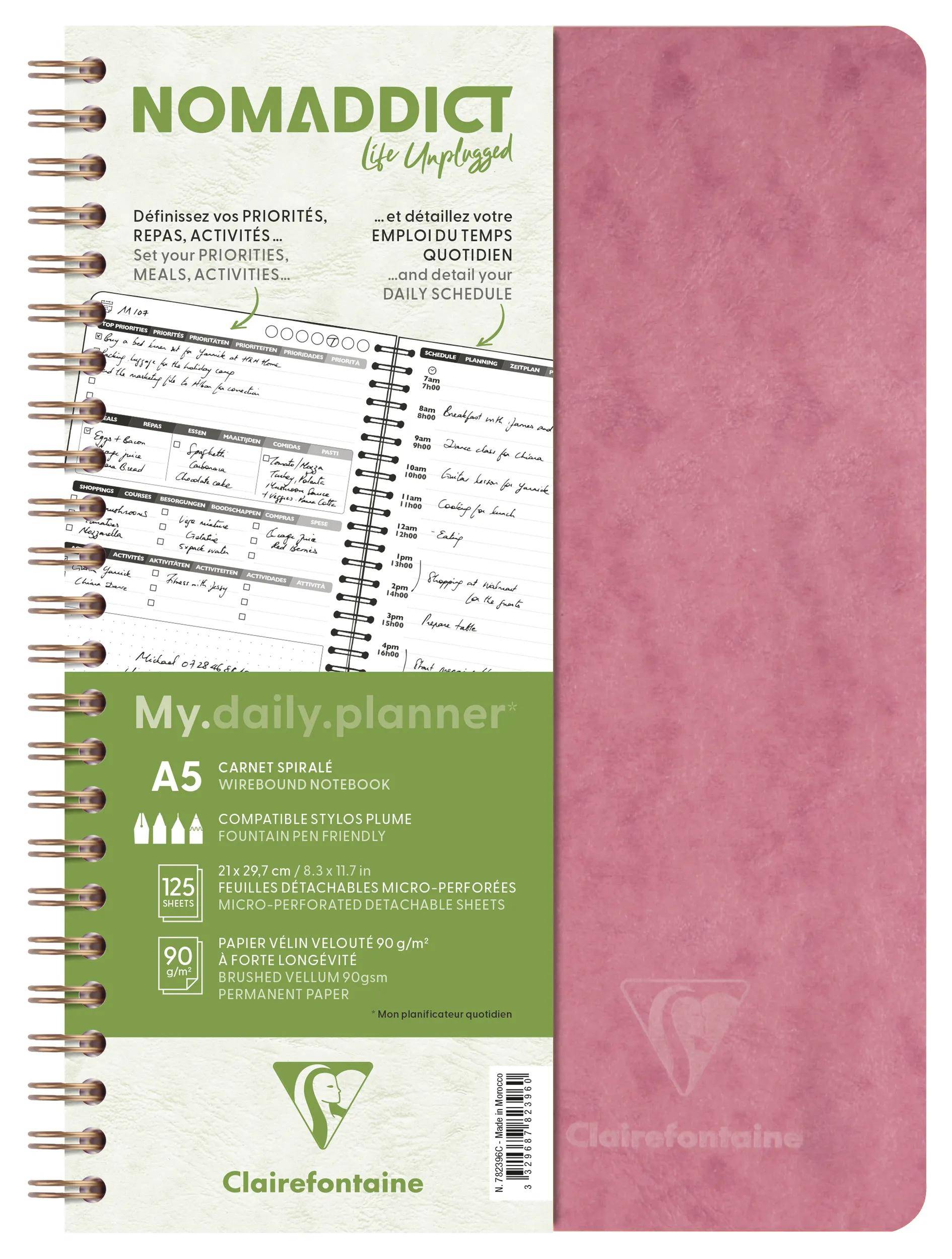 Rosa spiralgebundenes Nomaddict A5 Tagesplaner-Notizbuch mit französischem Text, Beispiel-Zeitplanseiten und Clairefontaine-Branding auf dem Umschlag.