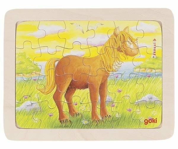 Eine Kinder-Rätselillustration eines Pferdes, das in einem grasbewachsenen Feld steht, mit einem Leuchtturm und Vögeln im Hintergrund, unter einem sonnigen Himmel.