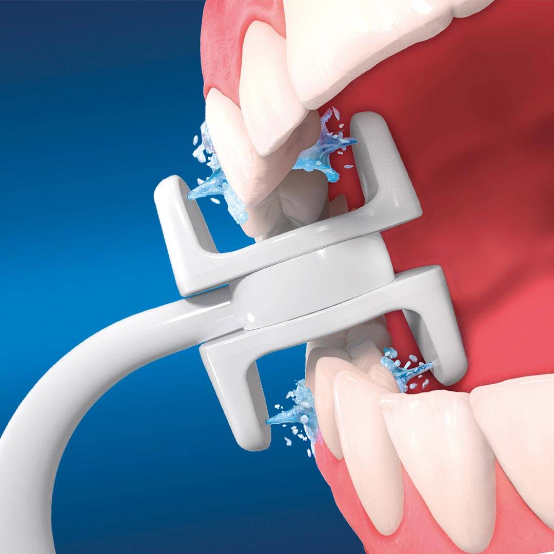 Zahnbürstenkopf reinigt Zähne mit Wasserspray auf blauem Hintergrund und demonstriert Mundhygiene.