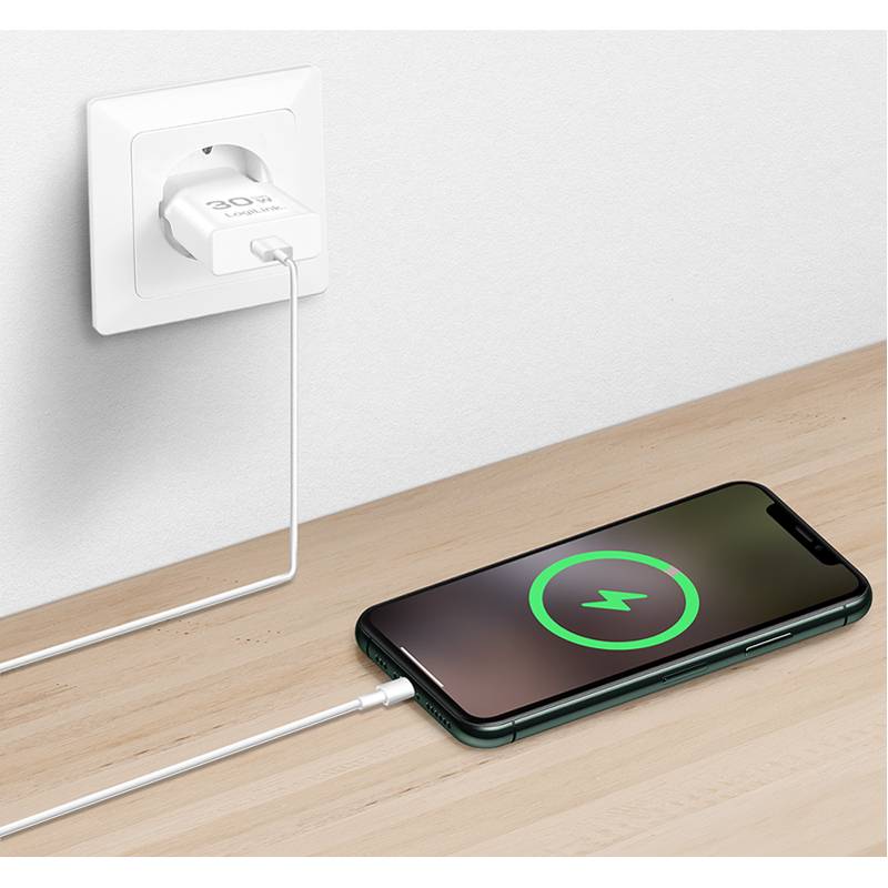 Ein Smartphone lädt auf einem Holztisch, durch ein Kabel mit einer Steckdose verbunden. Der Bildschirm des Telefons zeigt ein großes Ladessymbol.