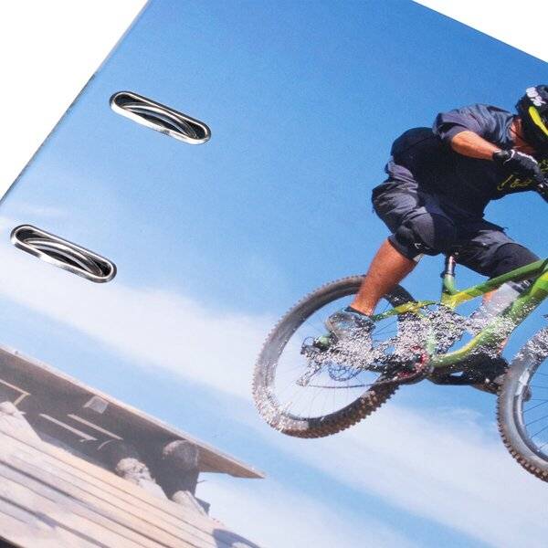 Mountainbiker auf einem grünen Fahrrad durch Wassergischt unter blauem Himmel, gezeigt auf dem Umschlag eines Spiralnotizbuches.