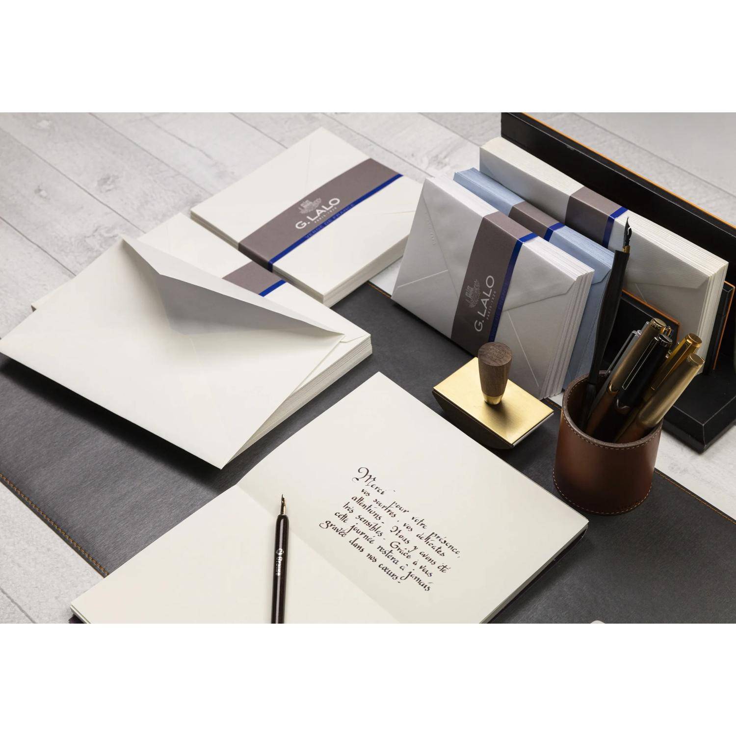 Elegantes Schreibwarenset mit Notizbüchern, Umschlägen, Stiften und bedrucktem 'G.LALO'-Briefpapier auf einem Schreibtisch.