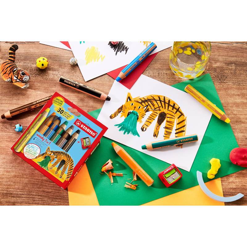 Ein Tisch mit bunten Bleistiften, Wachsmalstiften und Blättern Papier, die eine Kinderzeichnung eines orange-schwarzen Tigers zeigen. Ein Federmäppchen und ein kleines Spielzeug-Tiger sind ebenfalls zu sehen.