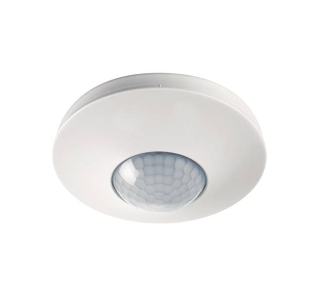 Ein weiß montierter Bewegungsmelder an der Decke mit einer halbkugelförmigen Linse, der zur Bewegungserkennung zum Aktivieren von Lichtern oder Alarmen konstruiert ist.