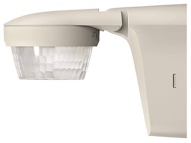 Ein beiges Bewegungsmelder mit sechseckiger Linse, auf einer Wandhalterung montiert, konstruiert zur Erkennung von Bewegungen in Innen- oder Außenbereichen.