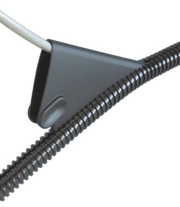 Eine graue Halterung mit eingefügtem Kabel ist an einer Wand montiert und hält ein aufgewickeltes Kabel. Die Halterung sichert das Kabel und verhindert dessen Bewegung.