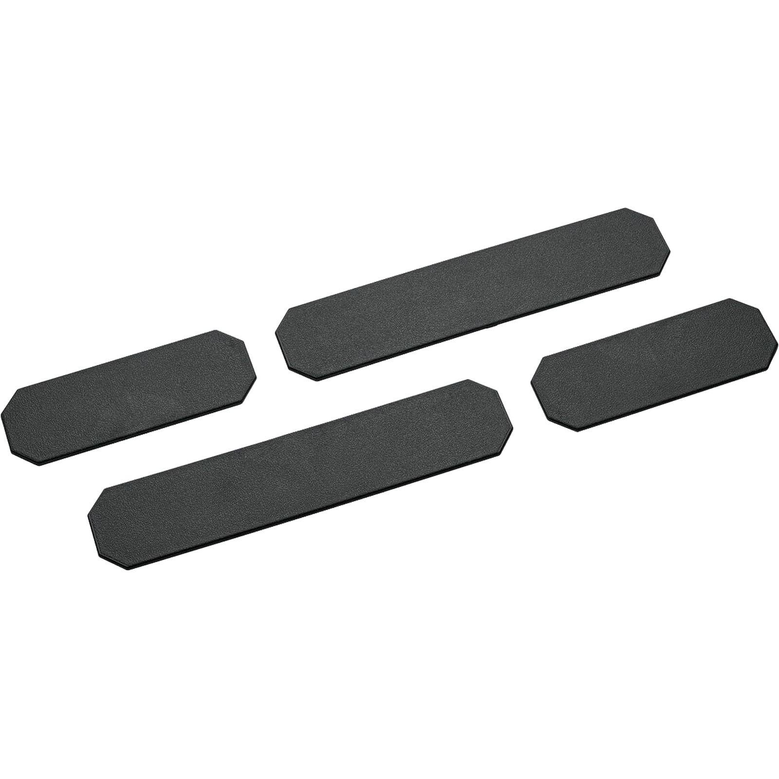 Vier schwarze Schaumstoffpaneele: zwei längere, zwei kürzere, in einem unregelmäßigen Muster auf weißem Hintergrund angeordnet.