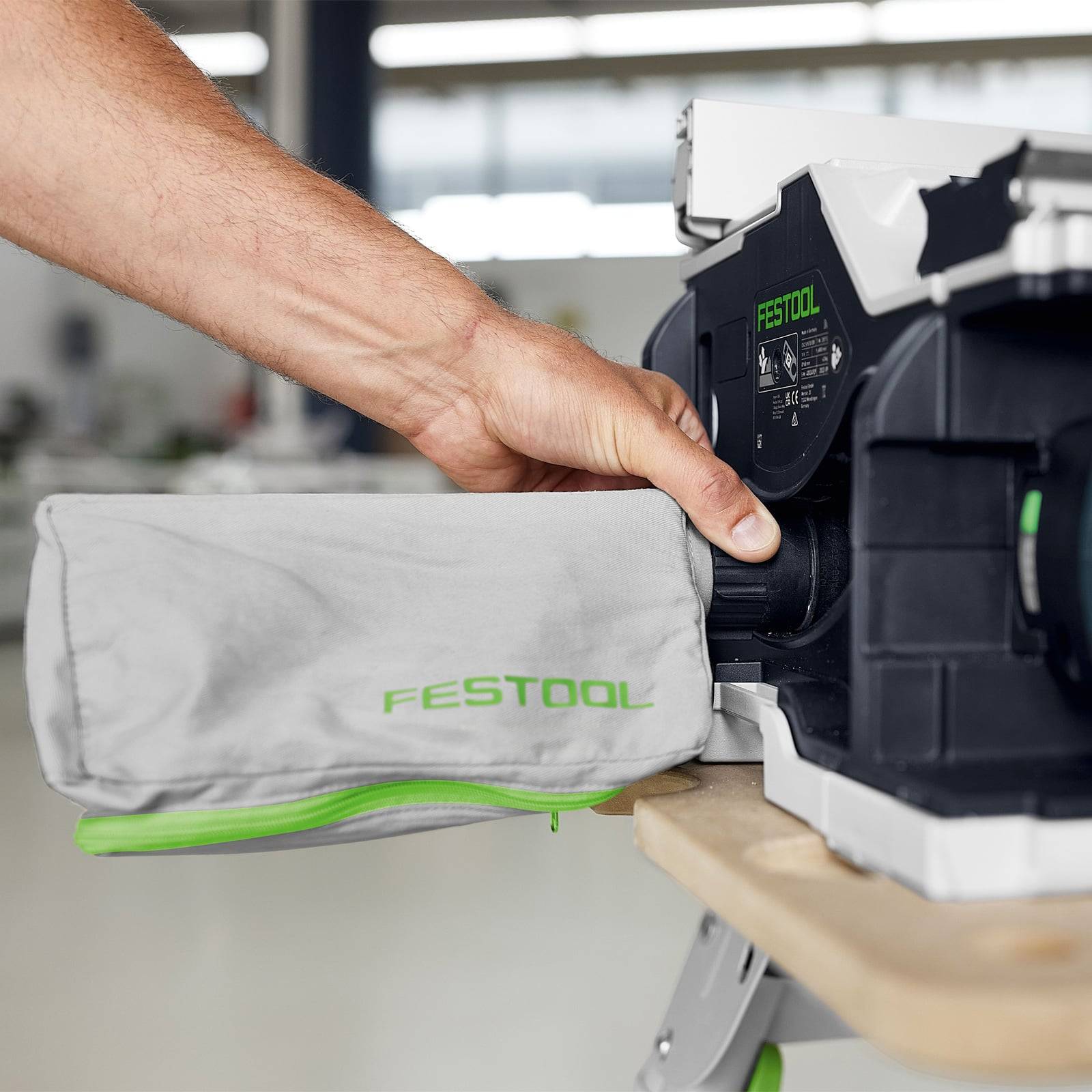 Eine Person, die einen Festool-Staubbeutel in ein Staubsaugersystem des Werkzeugs einlegt und dabei die Leichtigkeit der Installation und die Markenfokussierung veranschaulicht.