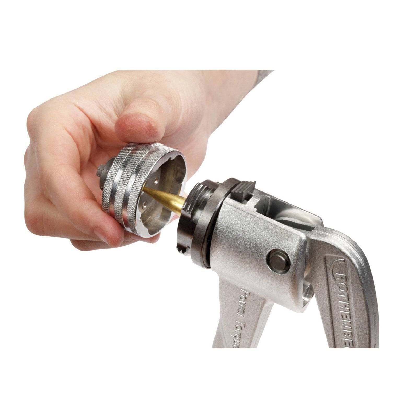 Eine Hand befestigt eine silberne Düse an einem metallischen mechanischen Werkzeug, was auf einen Einbau- oder Installationsvorgang hindeutet.