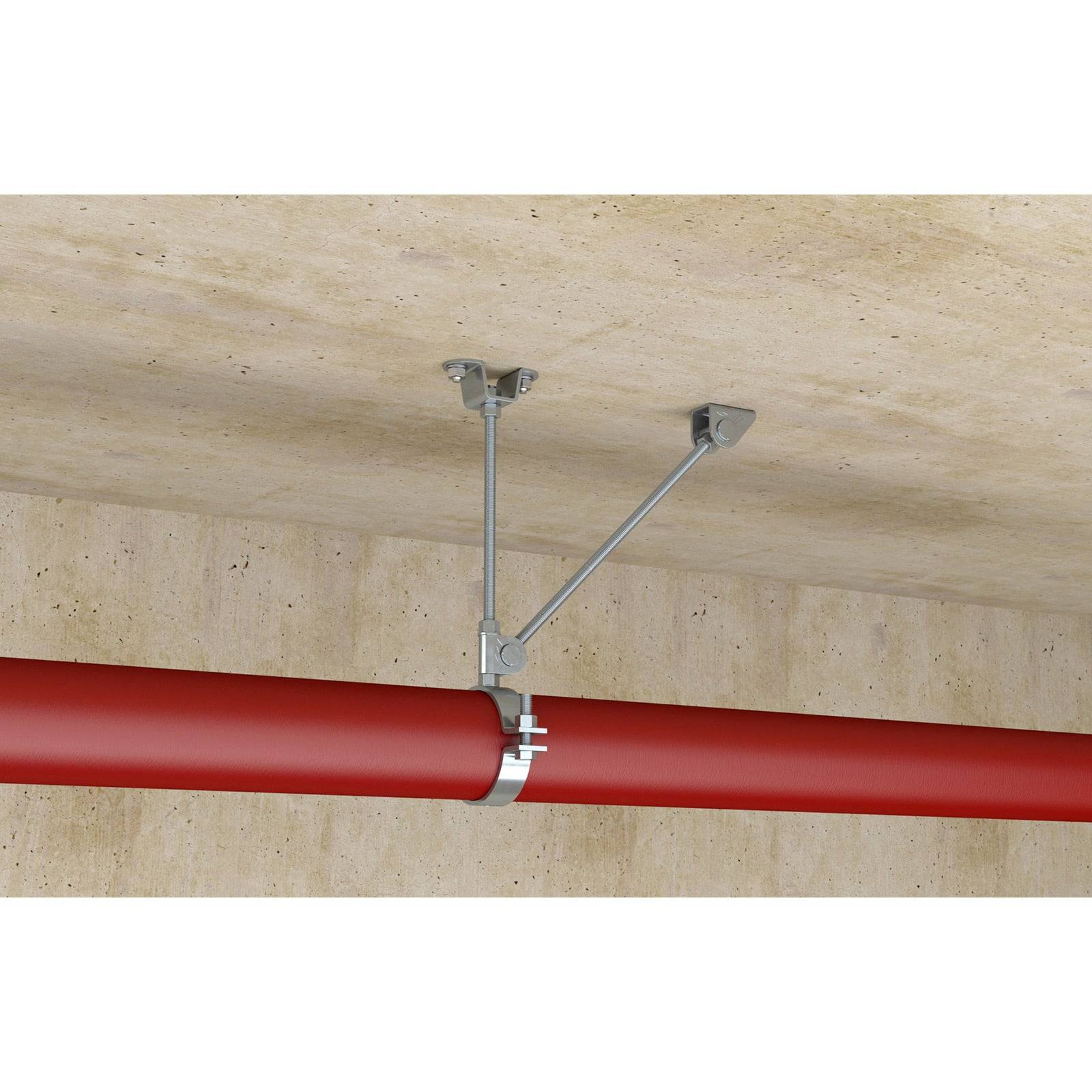 Eine rote Leitung ist mit einer Metallhalterung an einer beigen Decke und Wand befestigt.