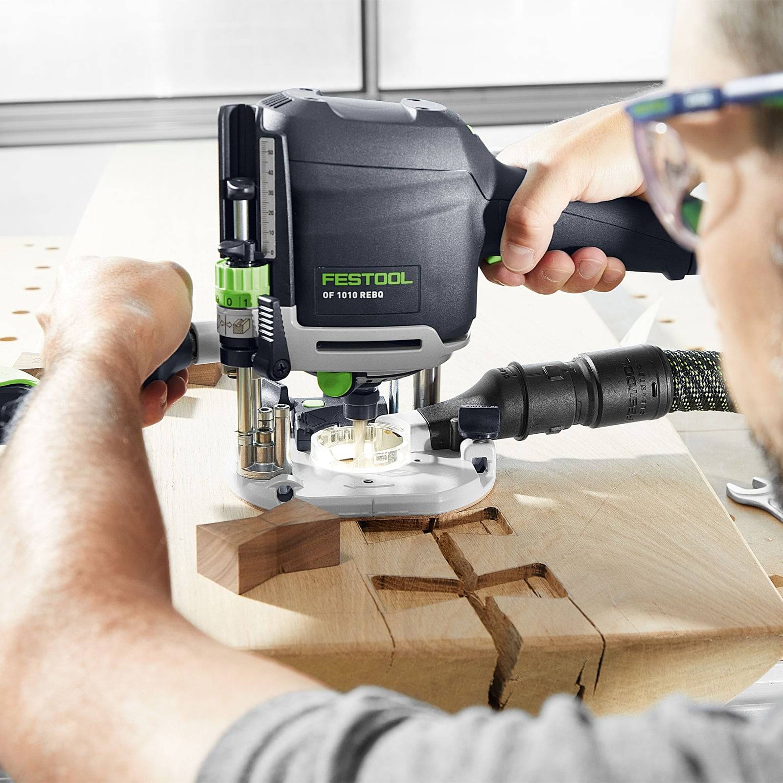 Eine Person, die einen Festool OF 1010 REBQ Oberfräser verwendet, um Holz zu formen. Das Werkzeug ist in Aktion und vollzieht präzise Schnitte auf der Holzoberfläche.