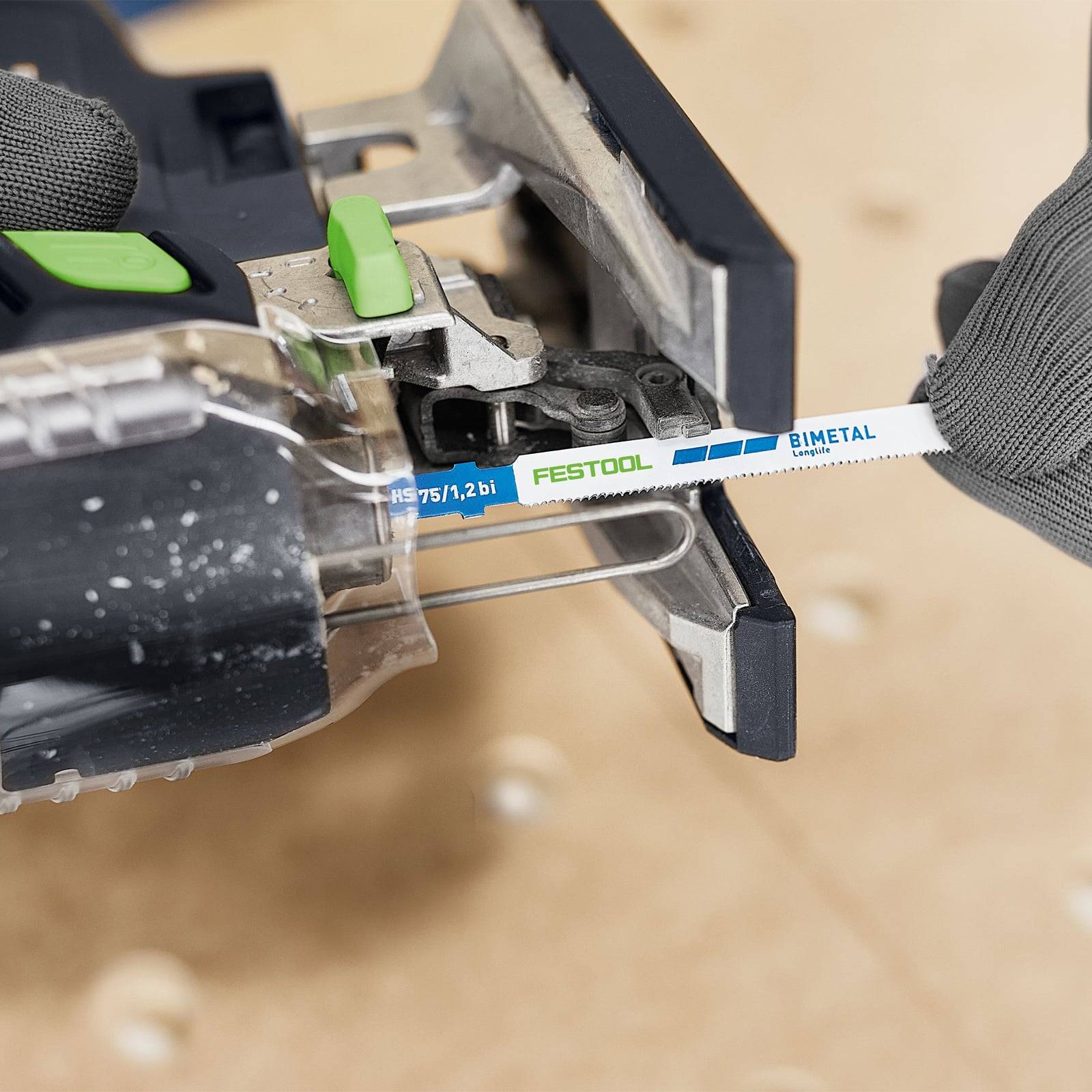 Eine Nahaufnahme einer Hand, die ein Stichsägeblatt vom Typ 'FESTOOL BIMETAL' in eine Stichsäge einführt und dabei das Design und die Kompatibilität des Sägeblatts präsentiert.