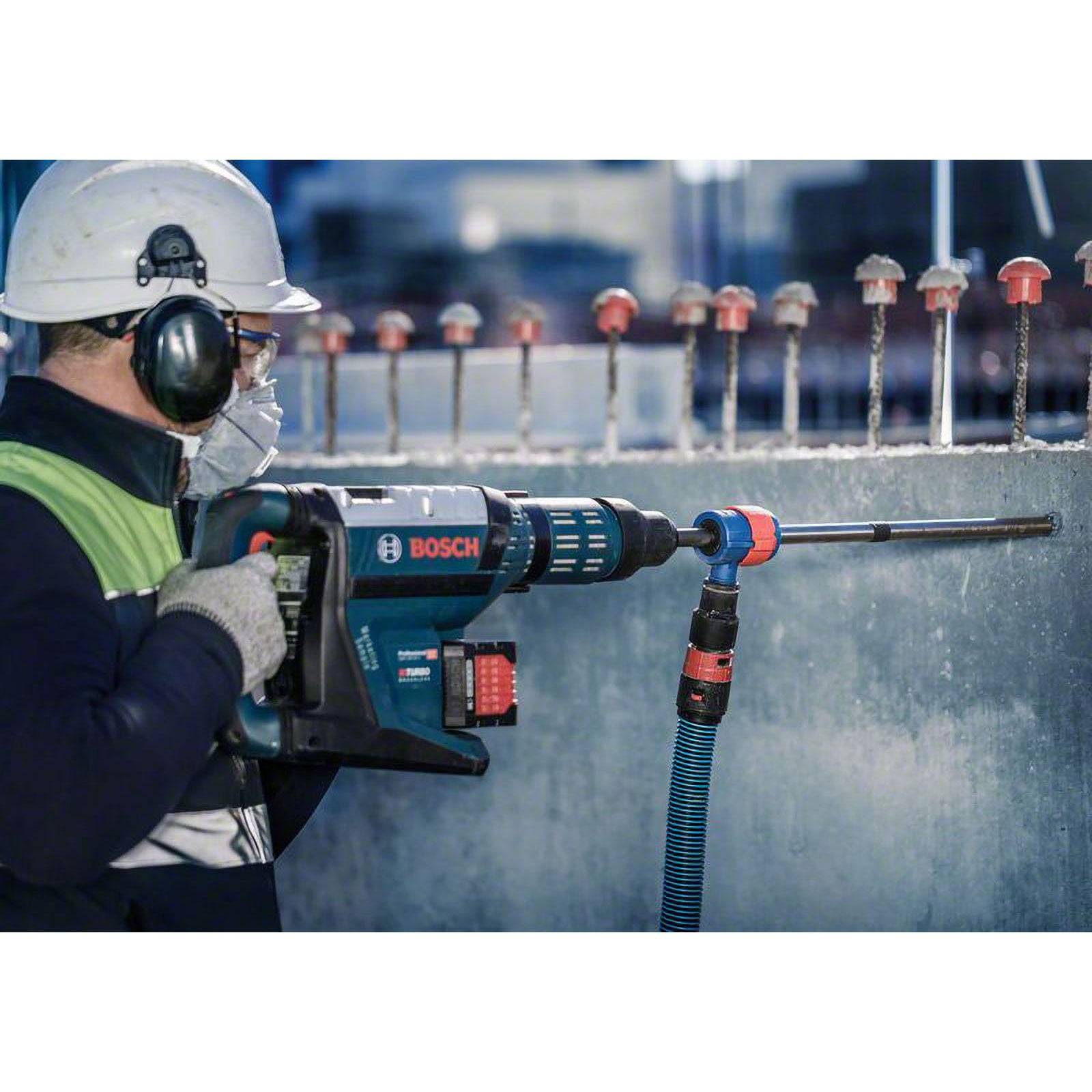 Ein Arbeiter mit Sicherheitsausrüstung benutzt einen Bosch-Bohrer, um in Beton zu bohren. Sicherheitsmaßnahmen wie Schutzkleidung und Gehörschutz sind deutlich erkennbar.
