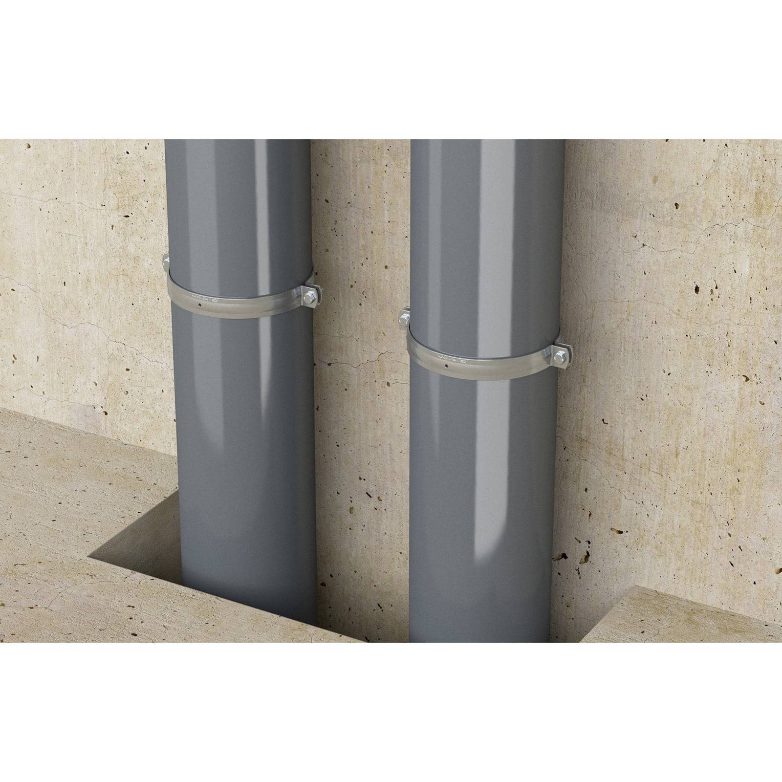 Zwei graue Rohre, die mit Metallhalterungen an einer Betonwand befestigt sind und aus einem eingelassenen Abschnitt eines Betonbodens herausragen.