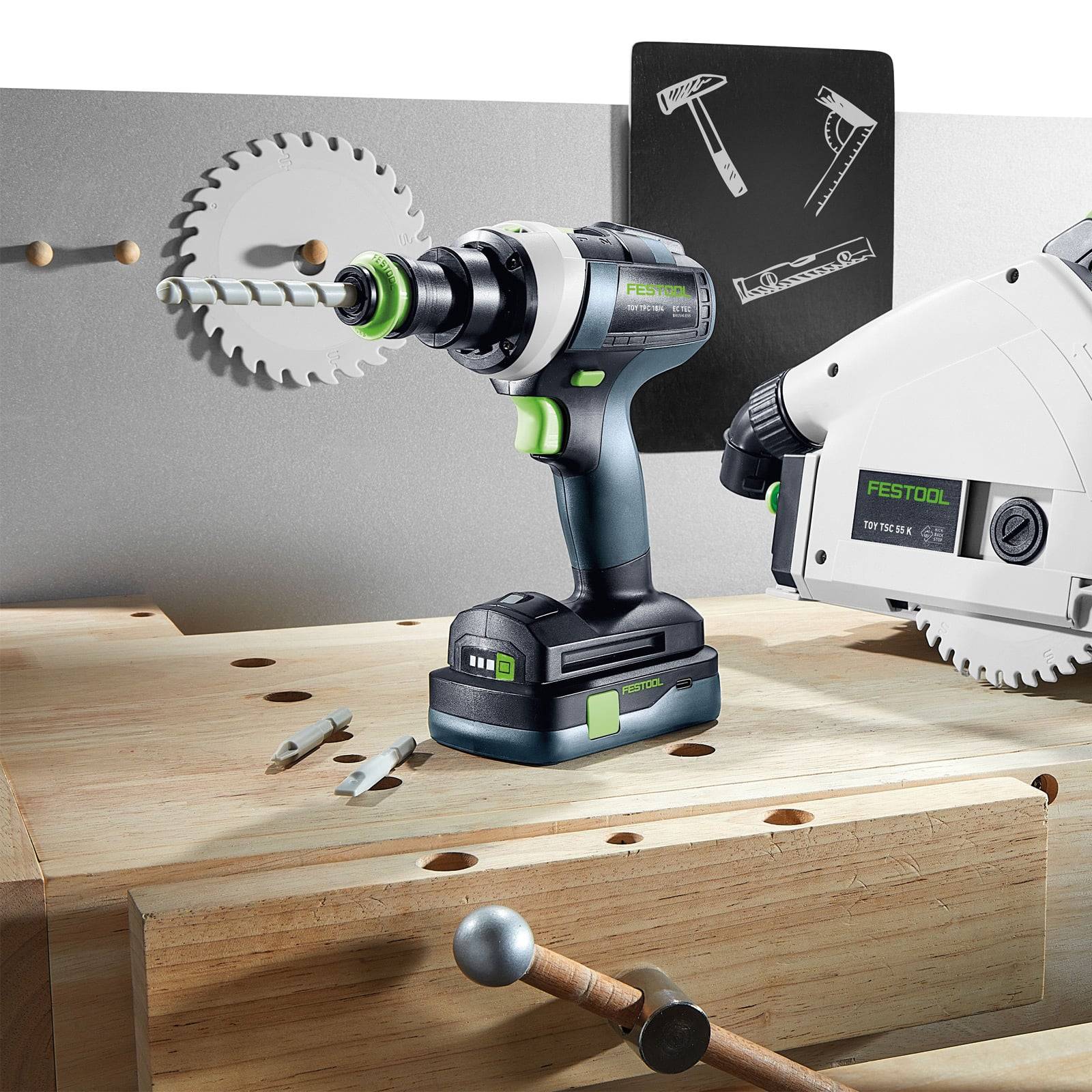 Eine Bohrmaschine und eine Säge auf einer Holzwerkbank, mit Metallwerkzeugen und Befestigungselementen in der Nähe verstreut. Die Bohrmaschine und Säge tragen die Marke ‚Festool'.