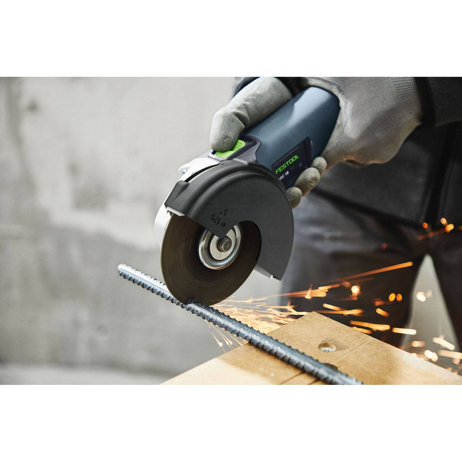 Eine Person, die einen Winkelschleifer verwendet, um eine Metallstange zu schneiden, wobei Funken sprühen und einen Prozess im Metallbearbeitungs- oder Baugewerbe veranschaulichen.