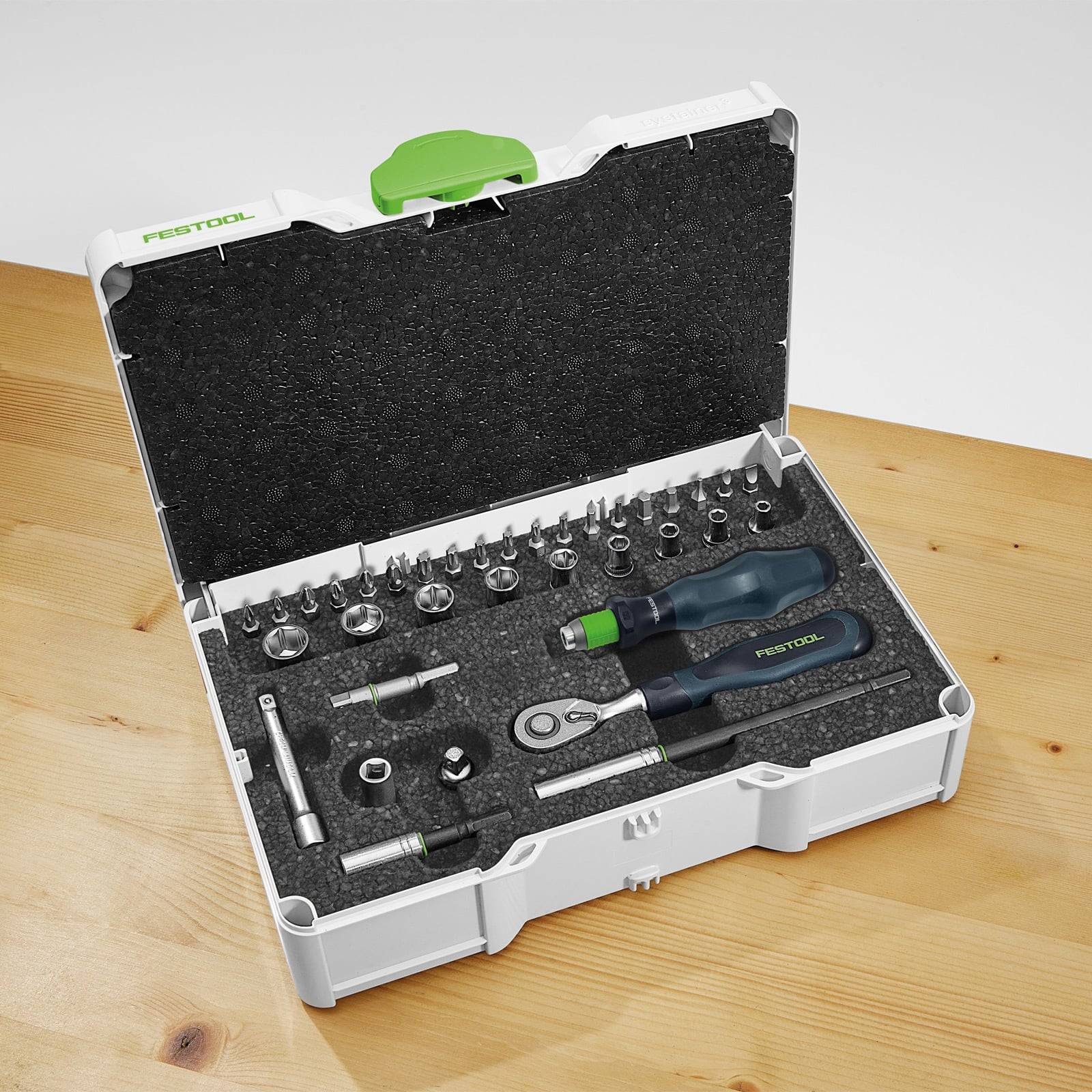 Ein Kunststoffkoffer auf einem Holztisch enthält einen Satz von Werkzeugen, darunter Steckschlüssel, Schraubendreher und Schraubenschlüssel, die ordentlich in Schaumstoff sortiert sind.