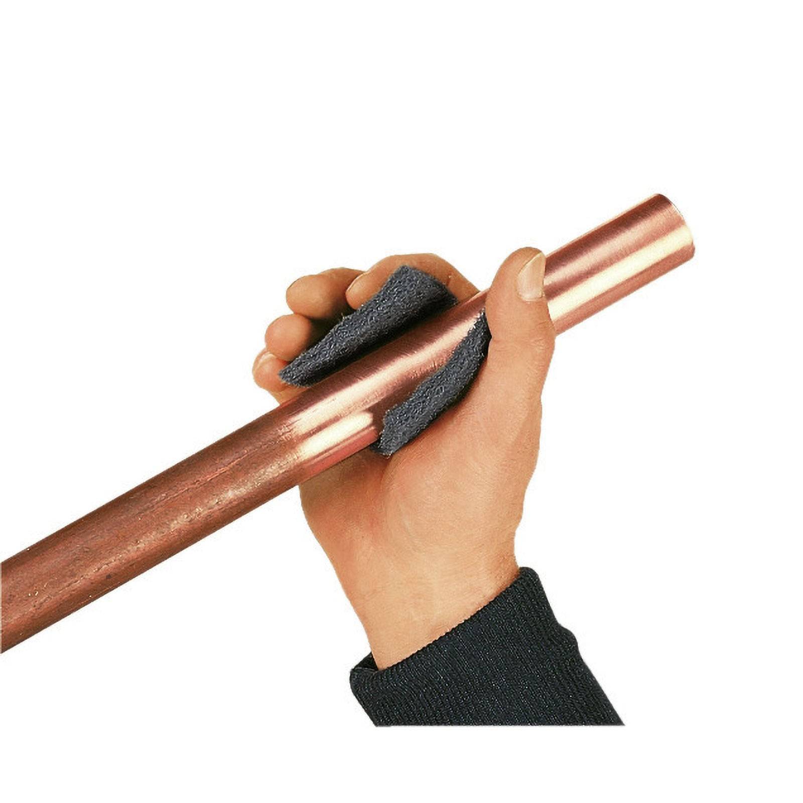 Eine Hand mit einem dunklen Handschuh poliert ein Kupferrohr mit einem Tuch und betont dabei die glänzende Oberfläche des Metalls.